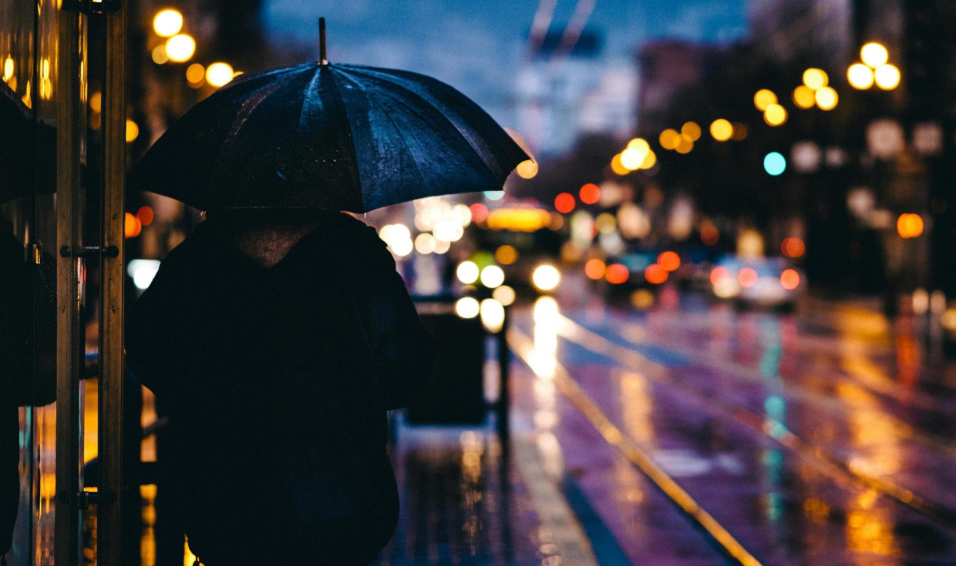 Inimene vihmavarjuga õhtusel tänaval