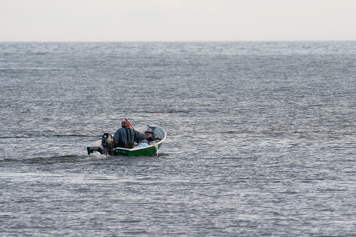 Fisherman on a boat at the sea. By: Karl Adami